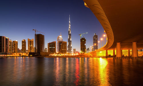 Bridge over river in city against clear sky