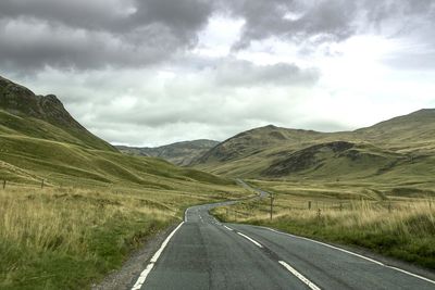 Road amidst green landscape against sky