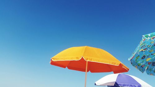 Low angle view of umbrella against clear blue sky