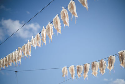 Low angle view of flags hanging against clear blue sky