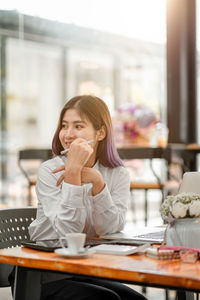 Portrait of young woman sitting on table at cafe