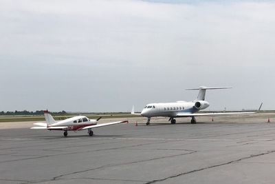 Airplane on airport runway against sky