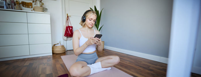 Portrait of young woman using mobile phone at home