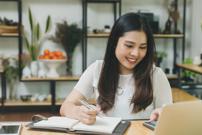 Young woman using phone on table