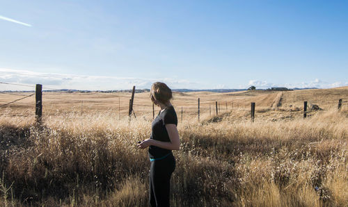Rear view of woman standing on field against sky
