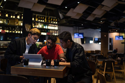 Friends using laptop while sitting in restaurant