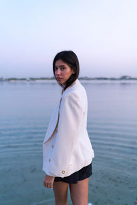 Portrait of a beautiful middle eastern woman standing in the water wearing a jacket