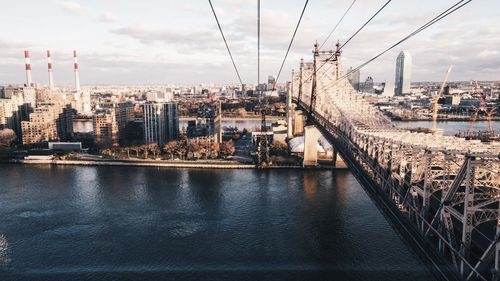 Queensboro bridge over east river by cityscape against sky