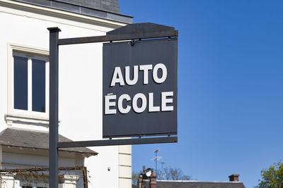 Low angle view of sign on building against blue sky