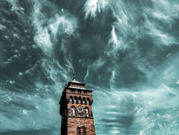 Low angle view of illuminated building by sea against sky at night