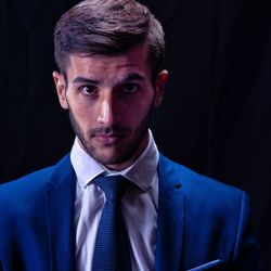 Portrait of young man in suit against black background