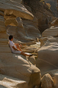 Rear view of woman sitting on rock