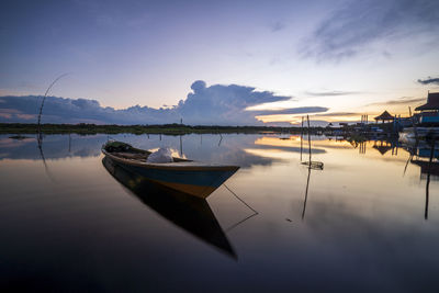 Boats moored in lake against sky during sunset