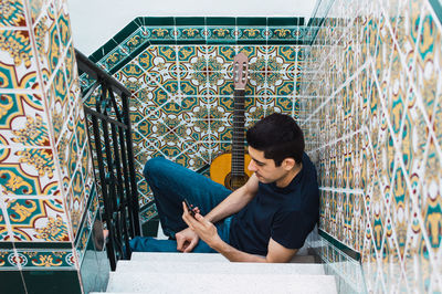 Man using a smartphone while resting from playing guitar at home.