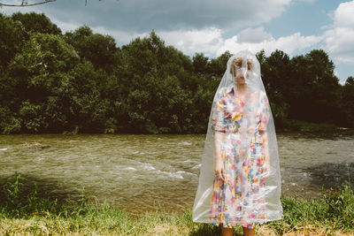 Woman wearing plastic while standing against lake