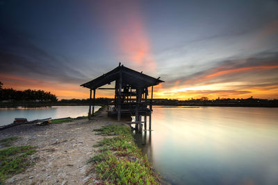 Pier over lake against sky during sunset