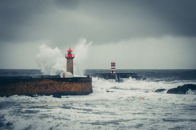 Lighthouse by sea against sky