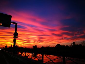 Silhouette city against dramatic sky during sunset