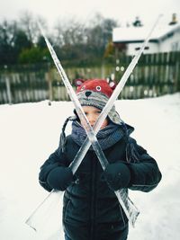 Portrait of boy holding ice while standing on snow covered field