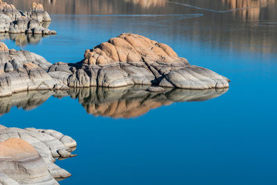 Rock formation by lake against blue sky