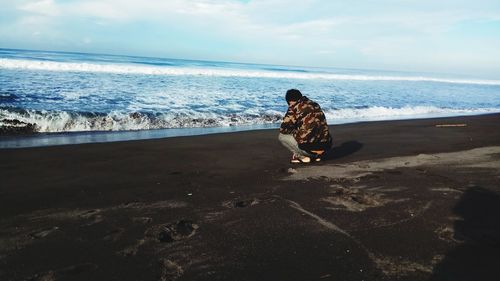 Rear view of woman sitting on beach