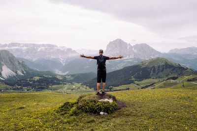 Rear view of man standing on mountain against sky