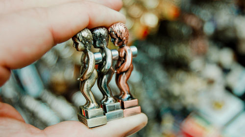 Close-up of human hand holding metallic figurines