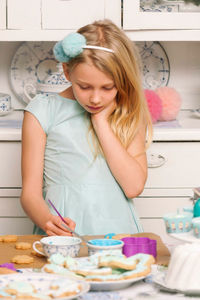 Girl making cookies at table in kitchen
