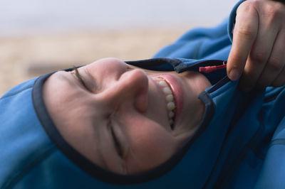 Portrait of a laughing woman in hooded fleece jacke by the shore. close-up