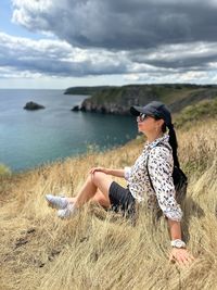 Young woman sitting on rock by sea