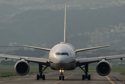 Airplane at airport runway against sky