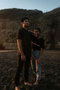 Young siblings standing on mountain against sky