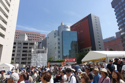 Group of people in city buildings against sky