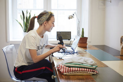 Podcaster using laptop while sitting on chair at home