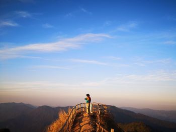 Woman standing at observation point against blue sky