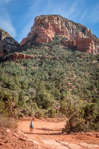 Rear view of woman hiking on dirt road