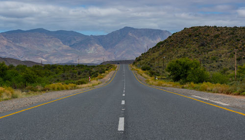 Empty road amidst mountains against sky