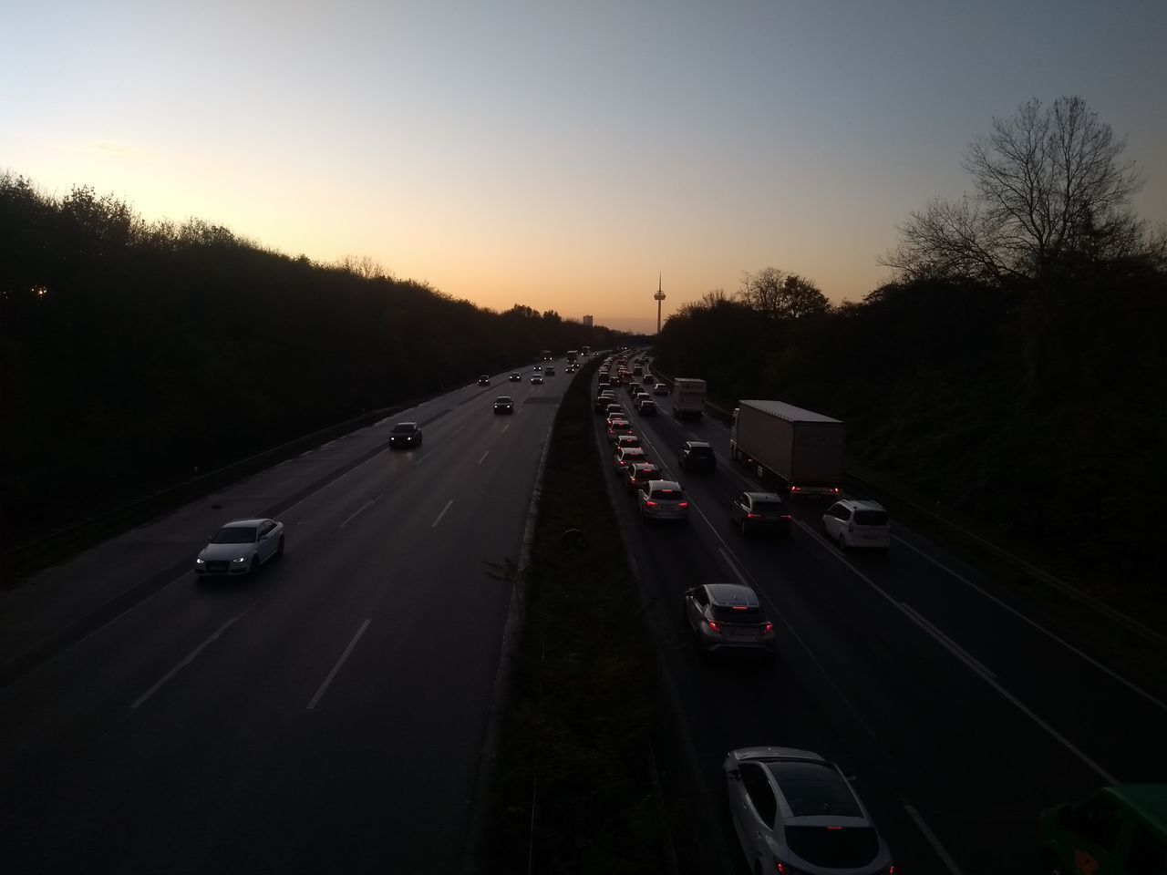 VEHICLES ON ROAD AGAINST SKY AT SUNSET