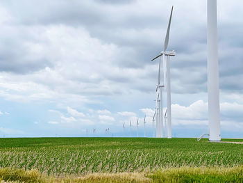 Wind turbines on field against sky