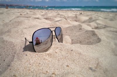 Sunglasses on beach against sky