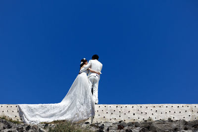 Low angle view of couple against blue sky