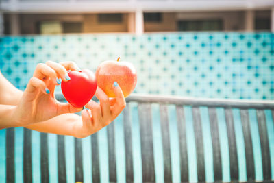 Cropped image of hand holding strawberry over swimming pool