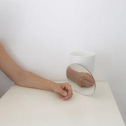 Close-up of woman hand on table against white background