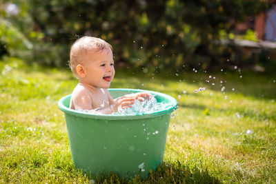 Cute baby girl playing in bucket at lawn