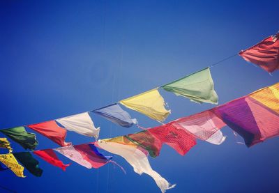 Low angle view of prayer flags against clear blue sky