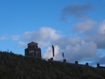 Low angle view of smoke stack on field against sky