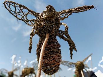 Low angle view of sculpture on rope against sky