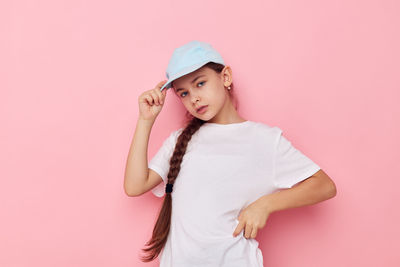 Portrait of young woman standing against pink background