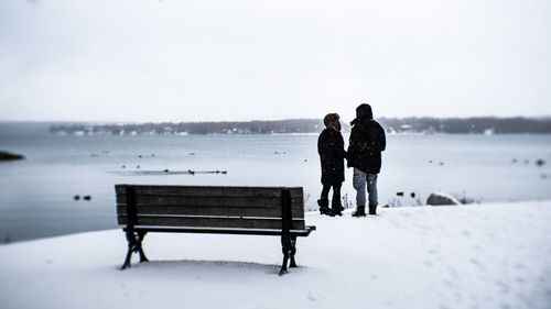 Rear view of man and woman on bench in winter