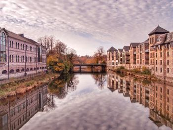 River amidst buildings and trees against sky